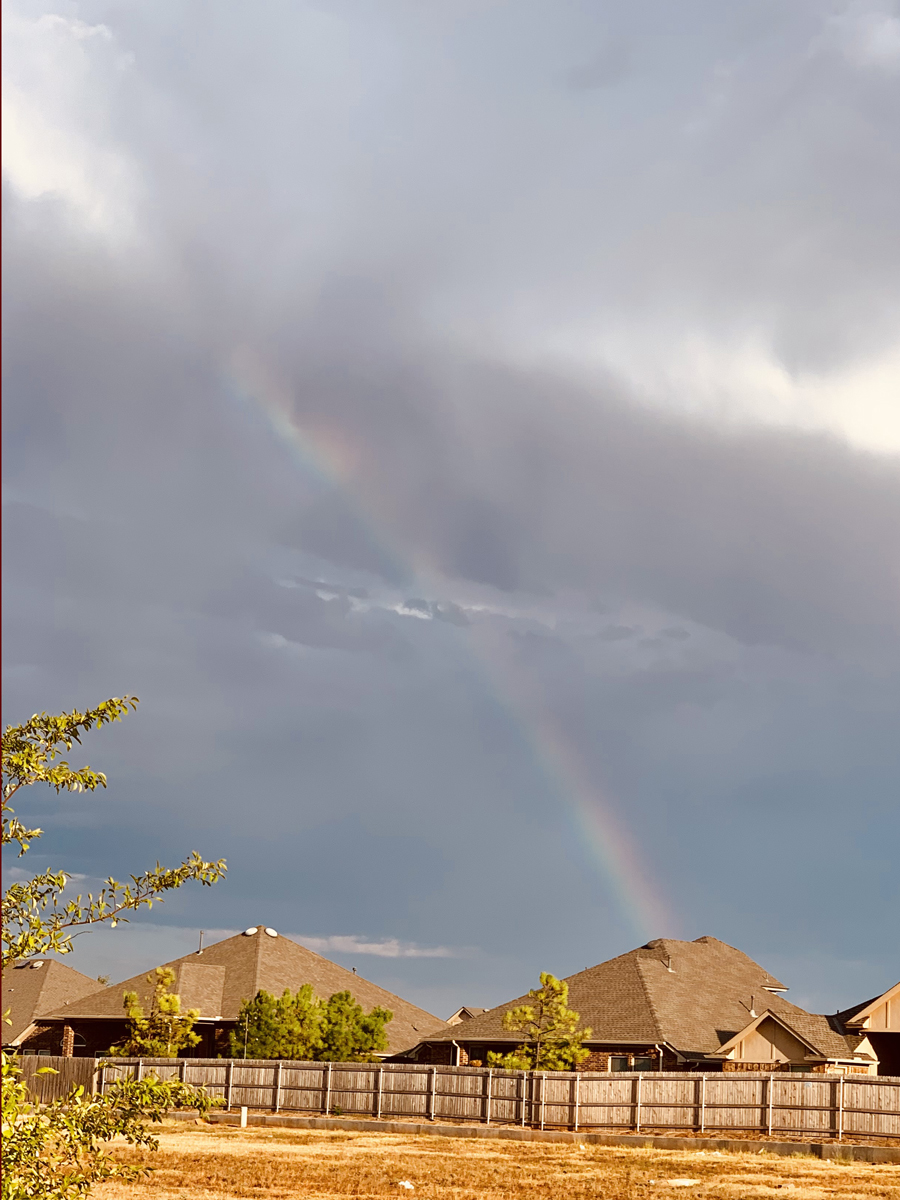 A beautiful rainbow shooting out from a cloud on a dark blue and grey day in our neighborhood